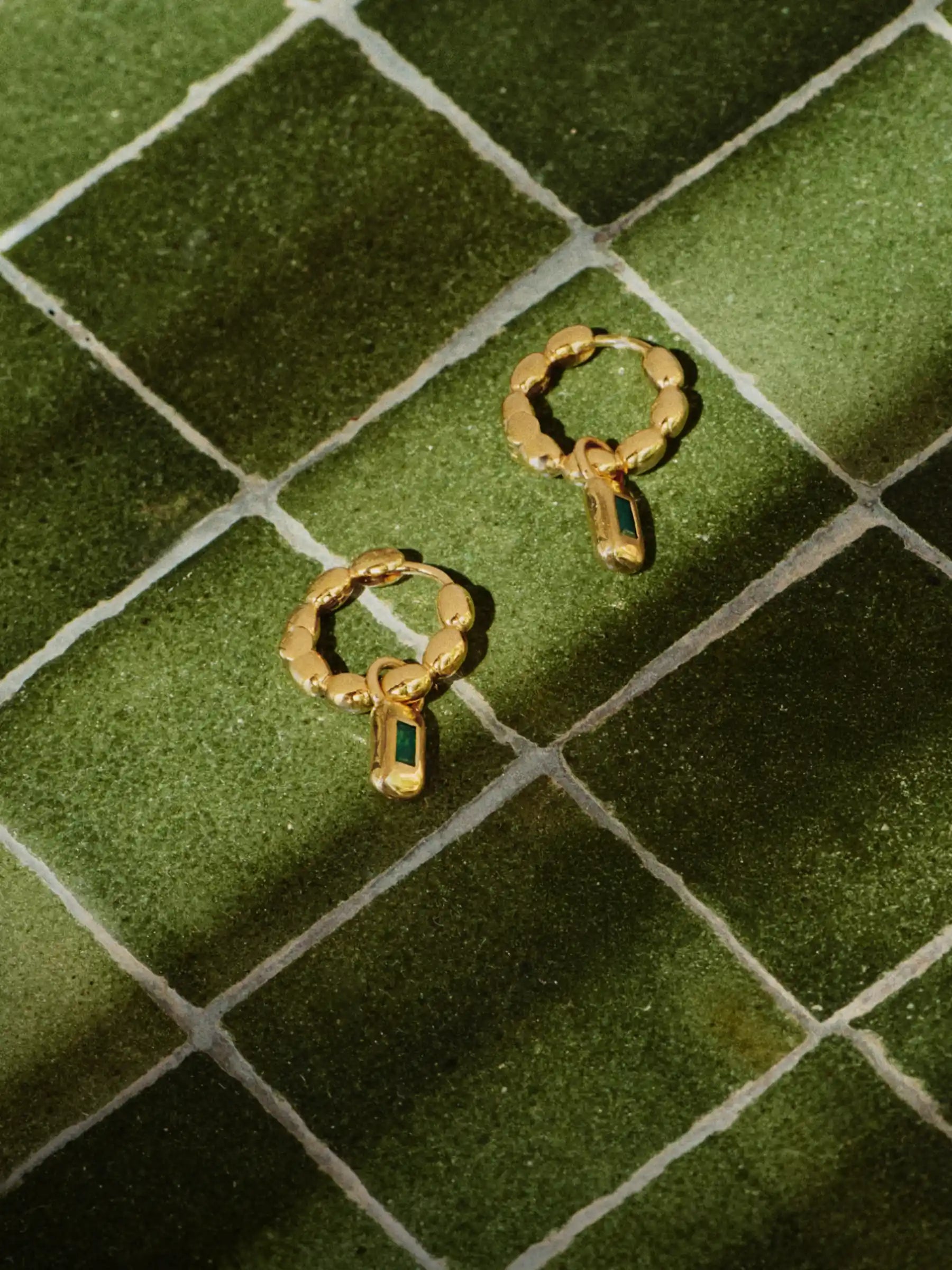 gold earrings on green tile flooring