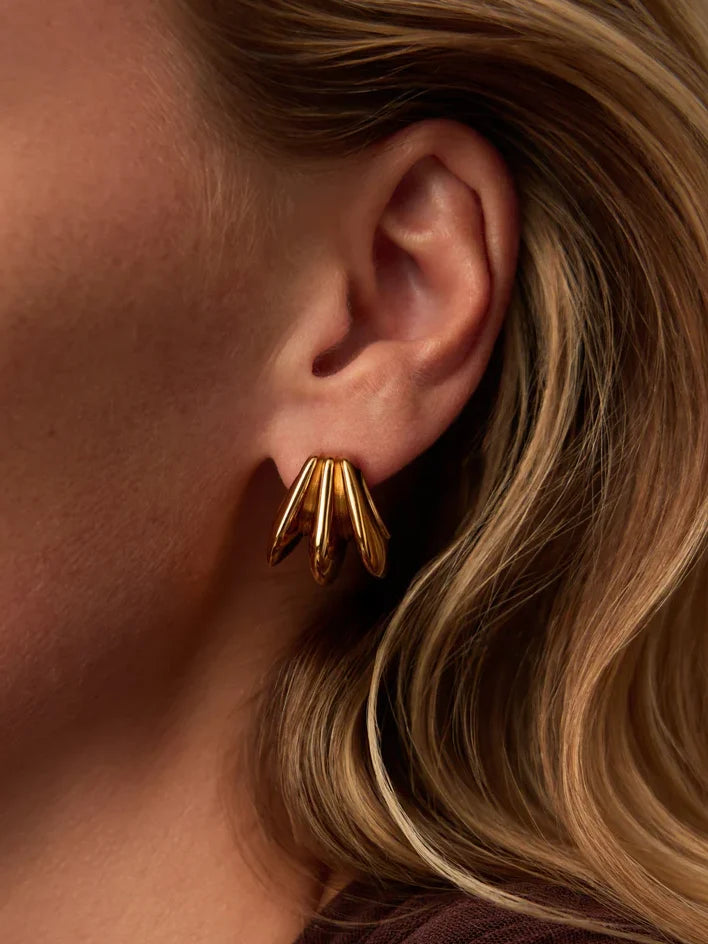 Gold earring worn by a person with blonde hair