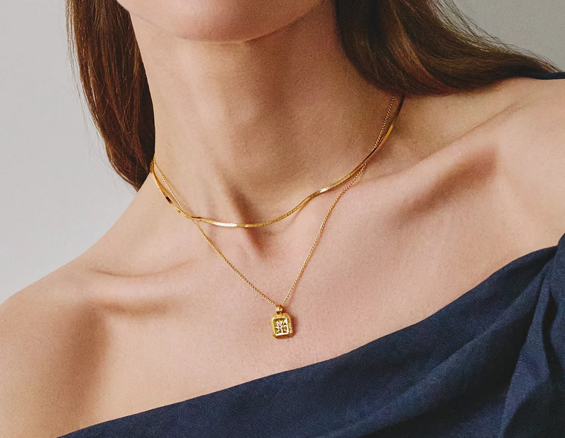 gold birthstone necklace layered with gold snake chain necklace