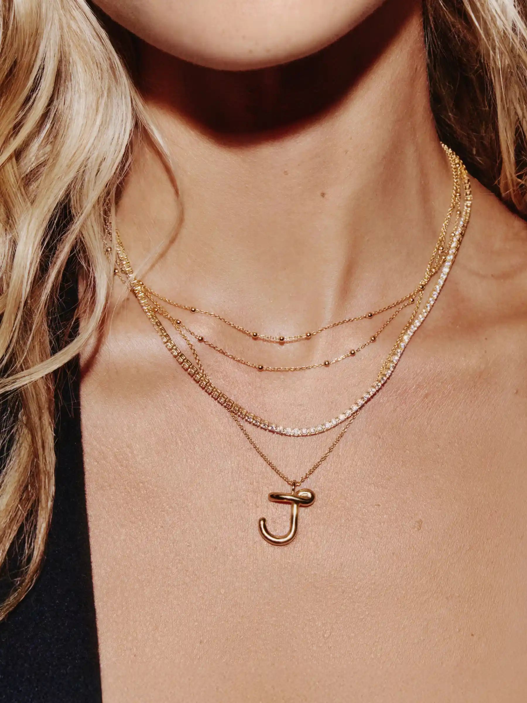 Layered gold necklaces with initial pendant on chain