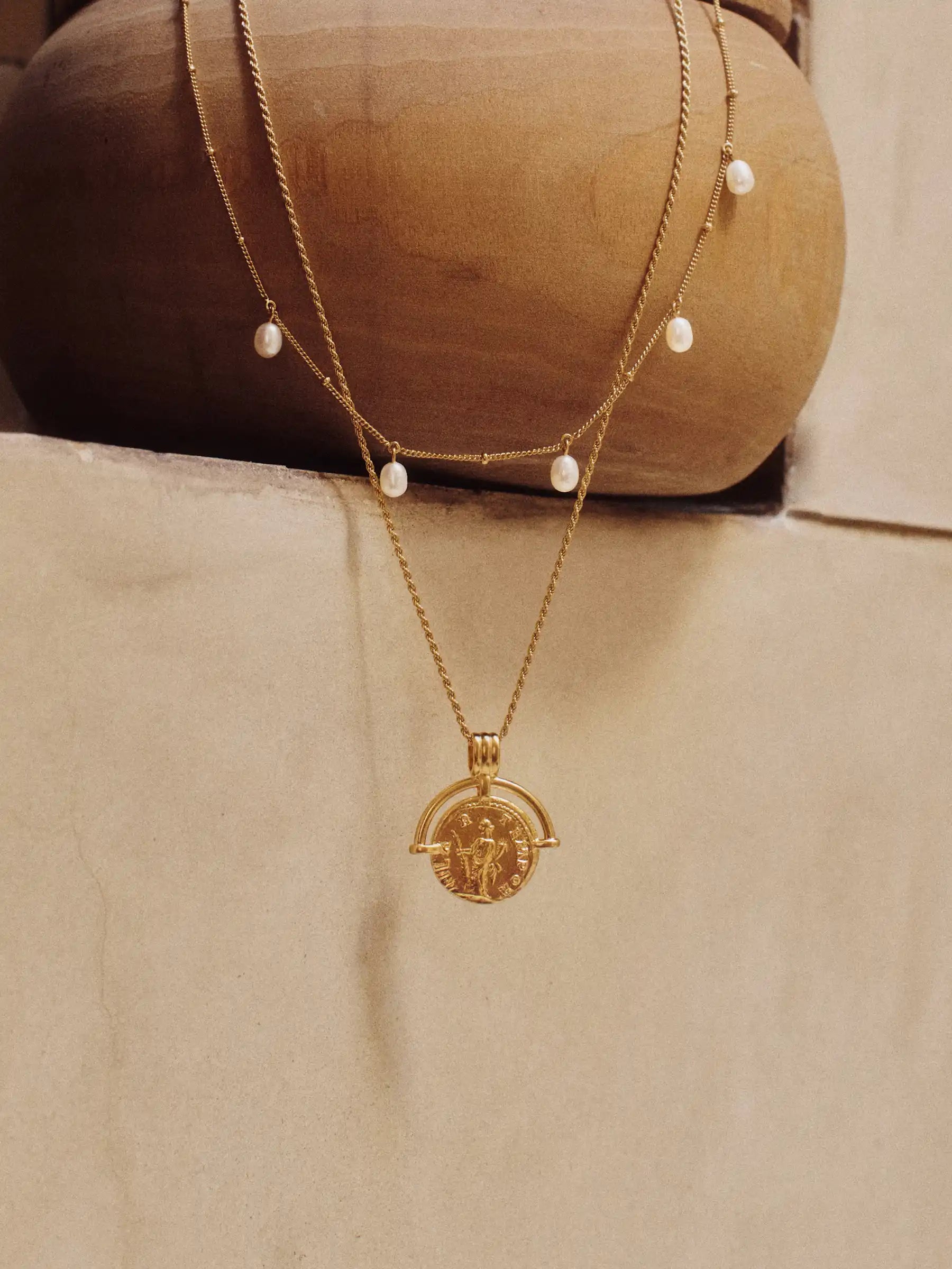 Gold necklace with a pendant on a wooden bowl