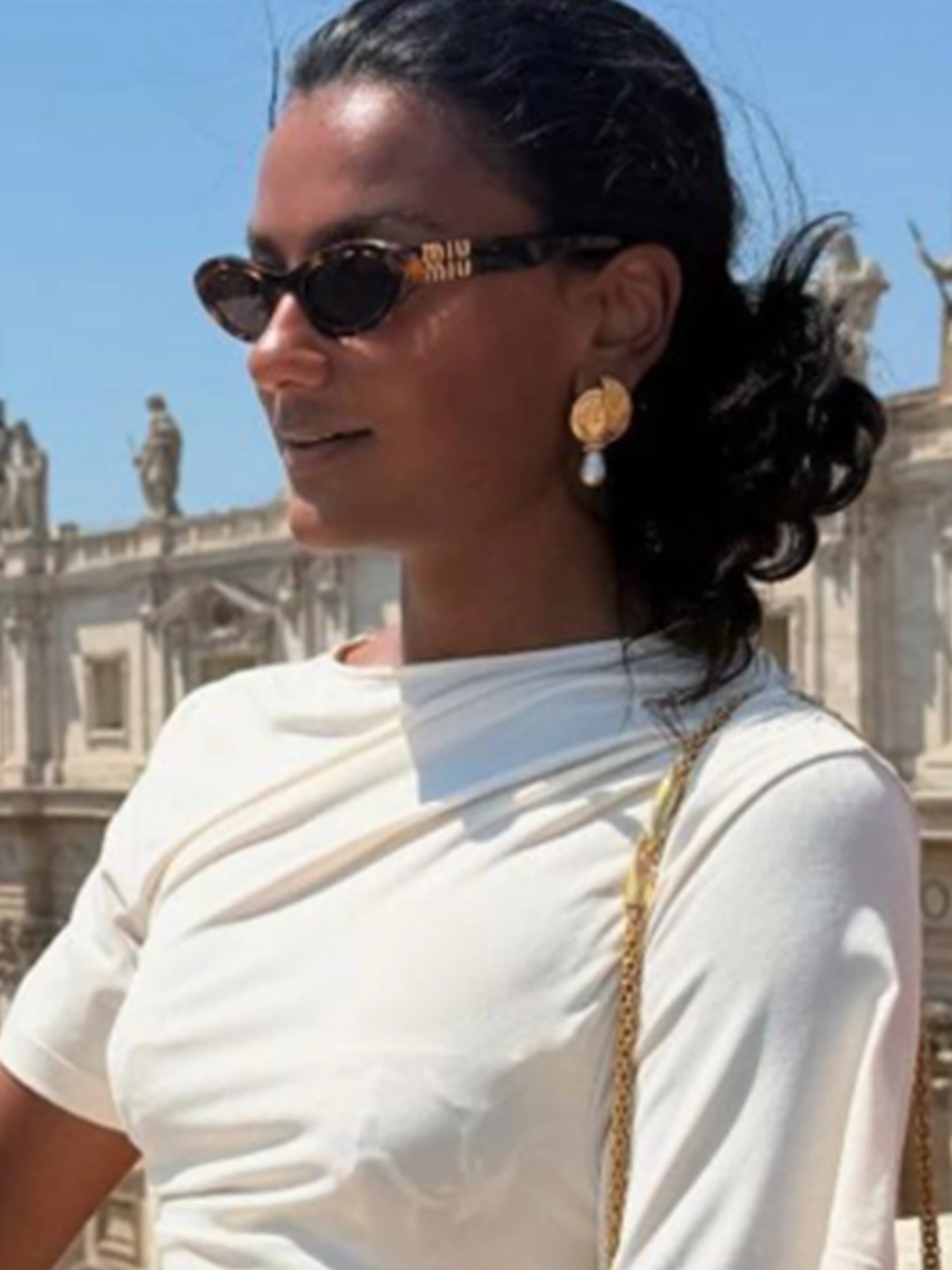 Woman wearing sunglasses and a white top with a blurred background
