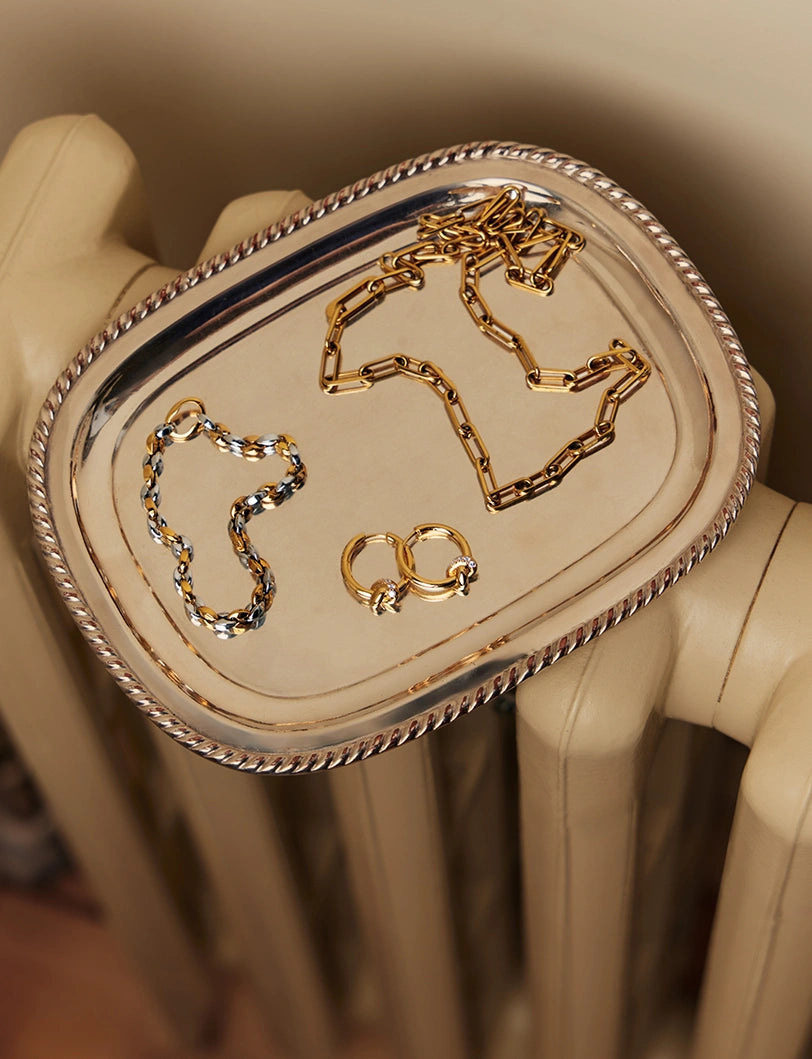 Gold bracelet with a bar charm engraved with '1995' on a light green background