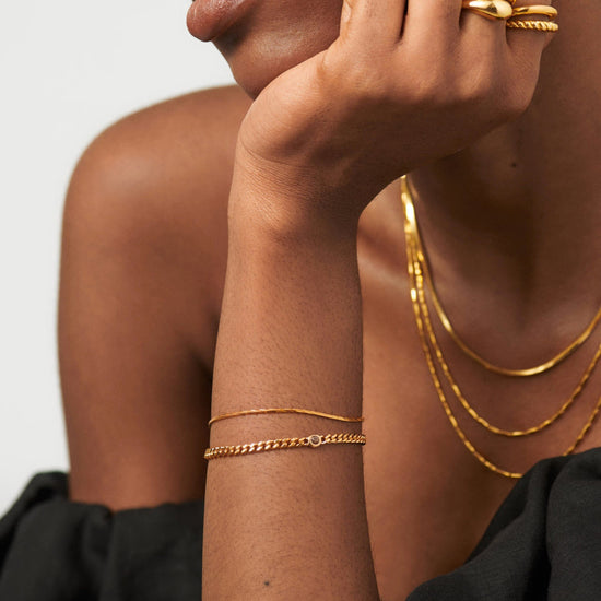 Gold birthstone bracelet stacked on wrist