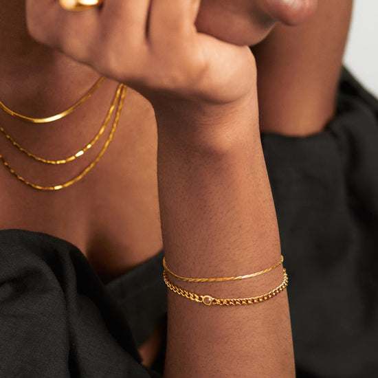 Gold birthstone bracelet stacked on wrist